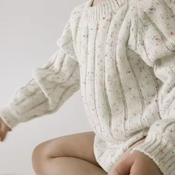 Organic speckled ribbed romper made from soft natural cotton, featuring snap buttons for easy nappy changes. Ethically made and comfy for all seasons.