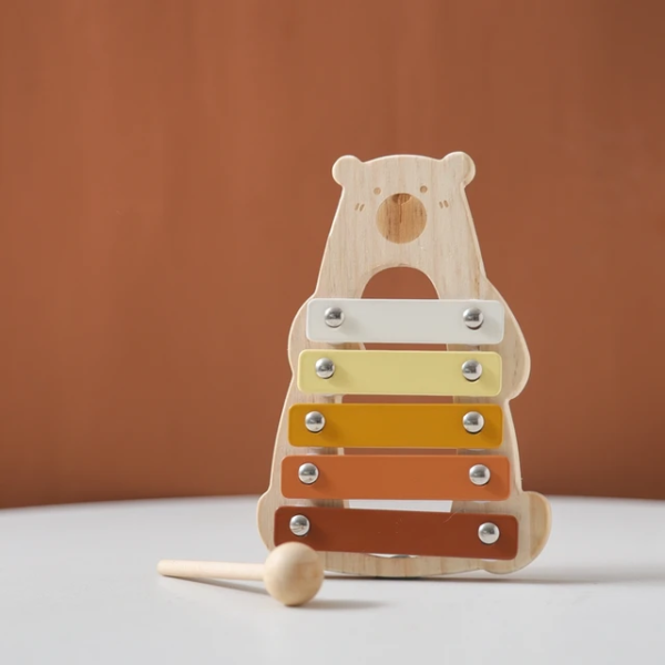 Toddler playing a wooden xylophone, developing motor skills and musical creativity.