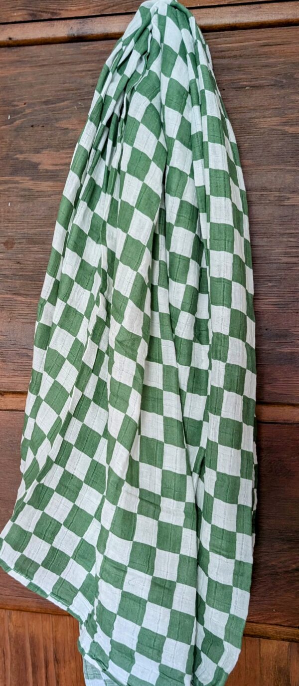 Soft muslin swaddle draped over a crib, ideal as a lightweight baby blanket.