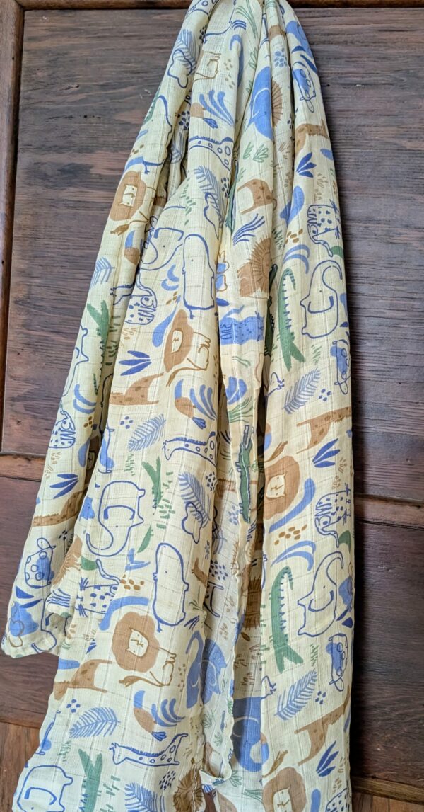 Freshly washed cotton muslin swaddle drying on a clothesline, showcasing its airy fabric